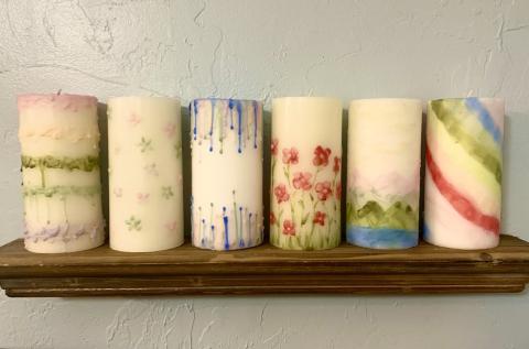 6 painted pillar candles on a shelf