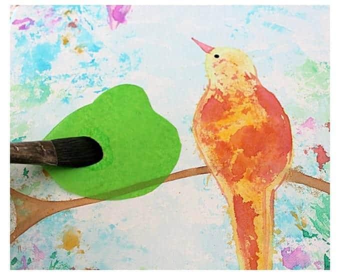 A painting in progress of a yellow and orange bird on a branch