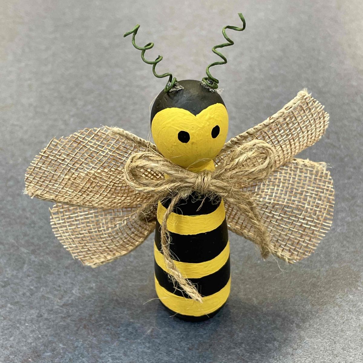 A painted toy wooden bee with burlap wings